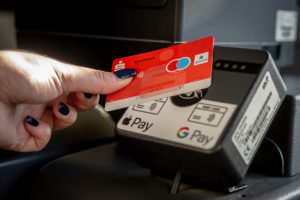 Eine Girokarte wird an ein Cashless Terminal im Bus gehalten, um bargeldlos zu bezahlen.