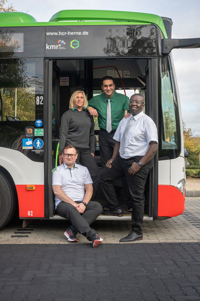 Kampagnenmotiv der HCR-Personalkampagne. Vier HCR-Mitarbeiter, eine Frau und drei Männer, stehen bzw. sitzen in der vorderen Tür eines Busses.