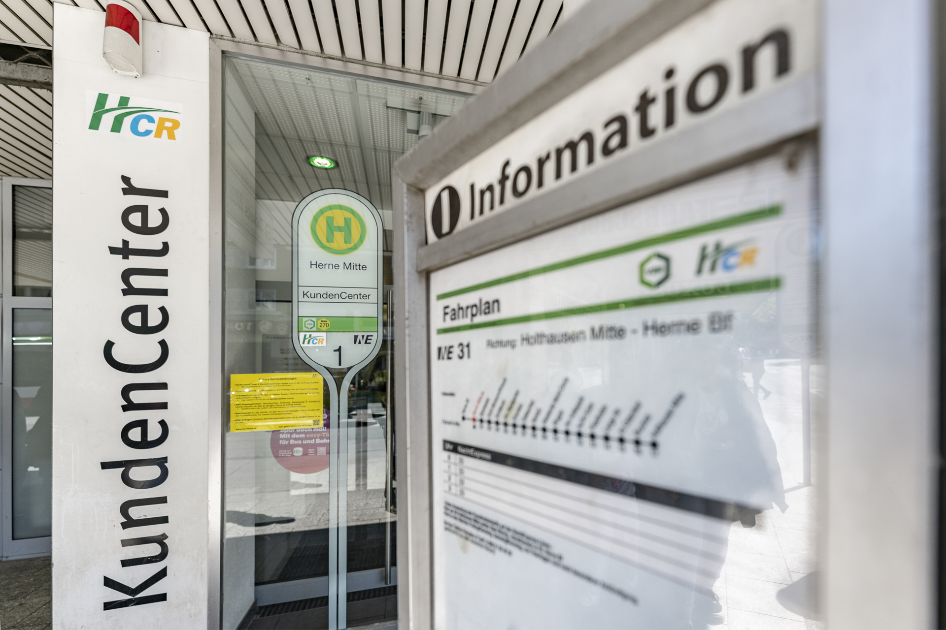 KundenCenter Herne Mitte von außen. Im Vordergrund ein Fahrplan der Haltestelle Herne Mitte