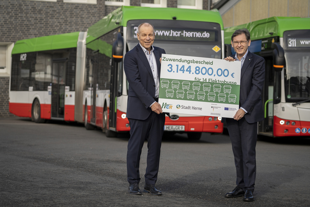 HCR-Geschäftsführer Karsten Krüger und Oberbürgermeister Dr. Frank Dudda mit einem Plakat zum Förderbescheid für 14 neue Elektrobusse auf dem HCR-Betriebshof
